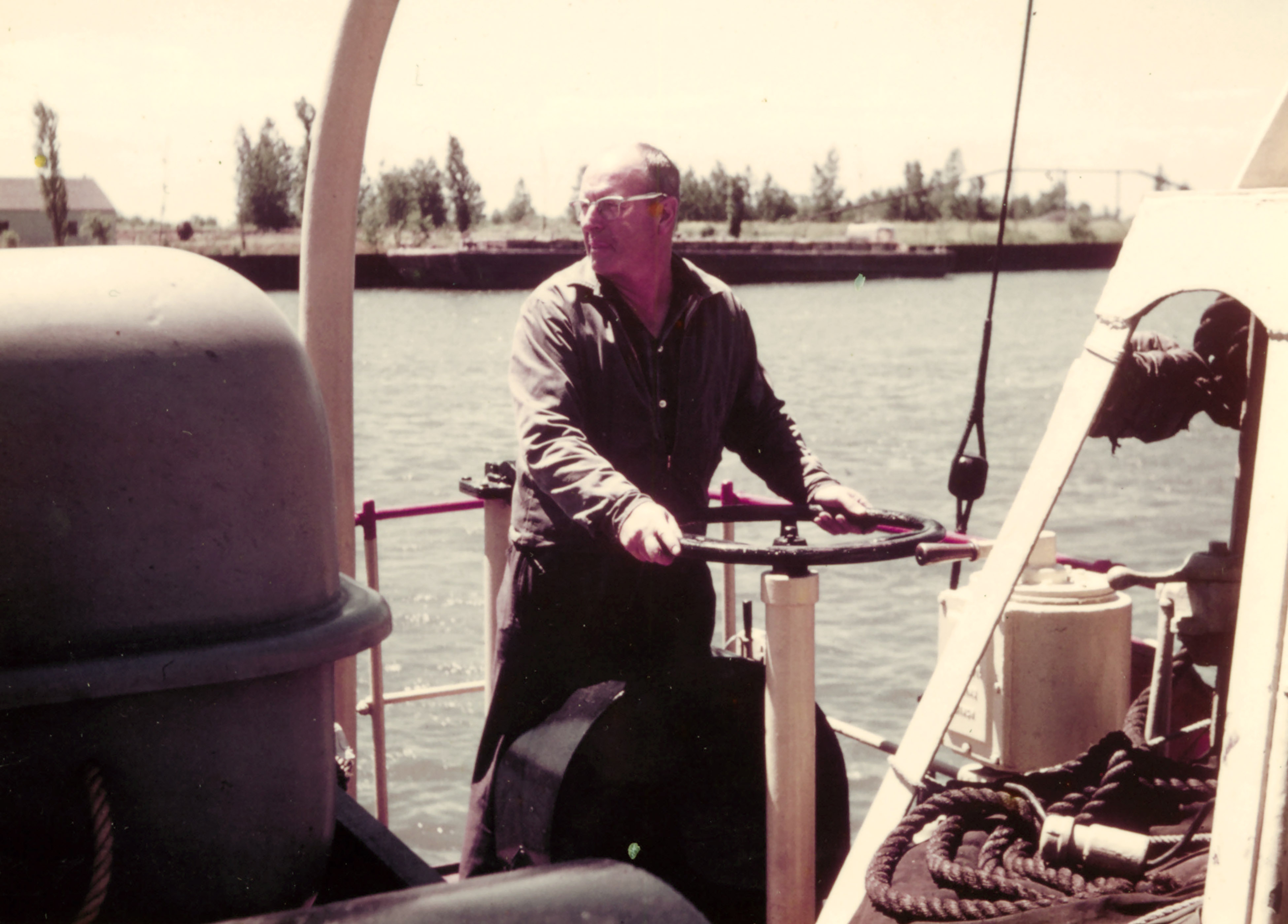 A uniformed man on deck of a ship pulling on a piece of equipment A uniformed man on deck of a ship pulling on a piece of equipment